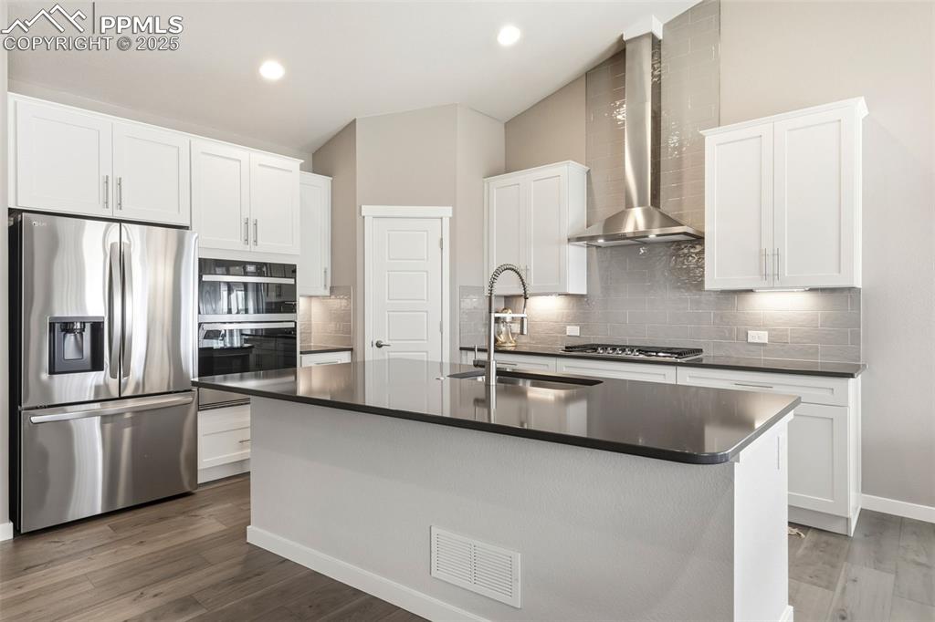 Image 16 of 49: Tile backsplash, stainless steel appliances include a gas cooktop