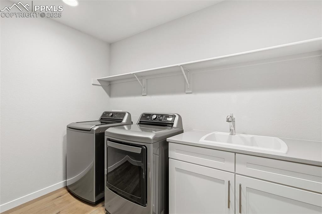 Image 26 of 49: Laundry room includes washer, dryer, sink & storage