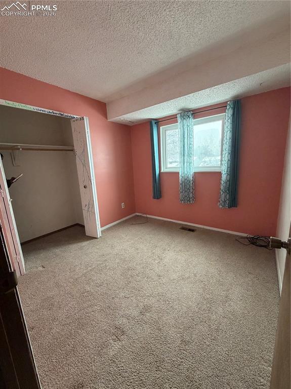 Image 10 of 12: Bedroom featuring a window, textured ceiling, and built-in closet with hang