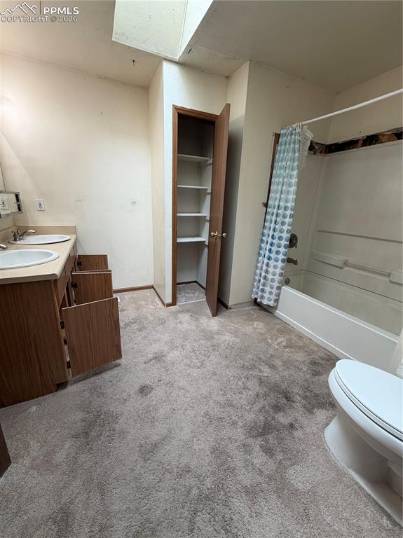 Image 12 of 12: Bathroom featuring a dual-sink vanity with wood-finish cabinetry, a built-i