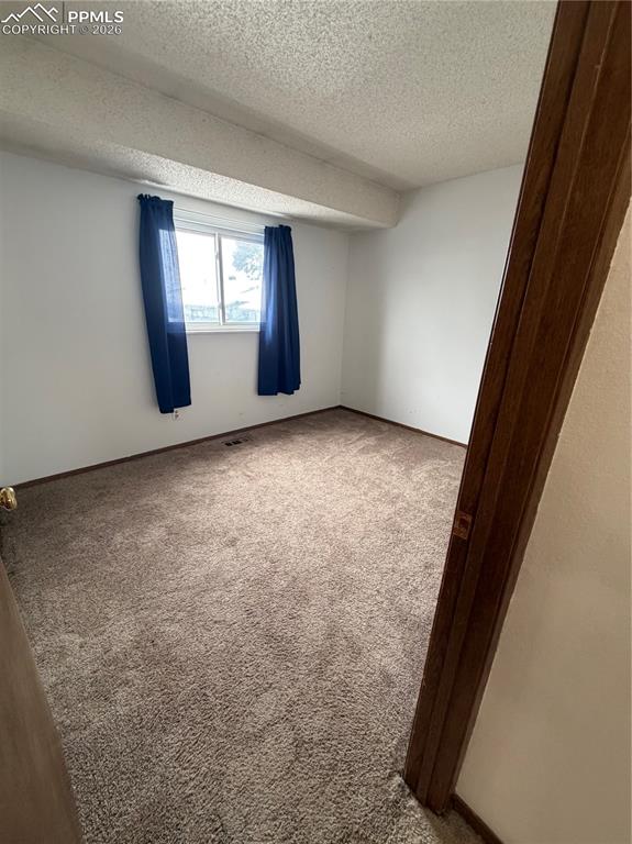 Image 6 of 12: Carpeted interior space featuring white wall finishes and a single window w