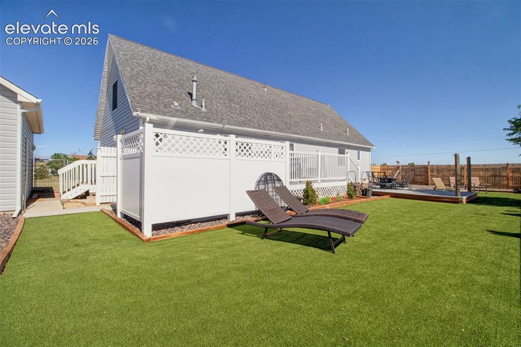 Image 30 of 43: Large backyard with green turf grass for low maintenance