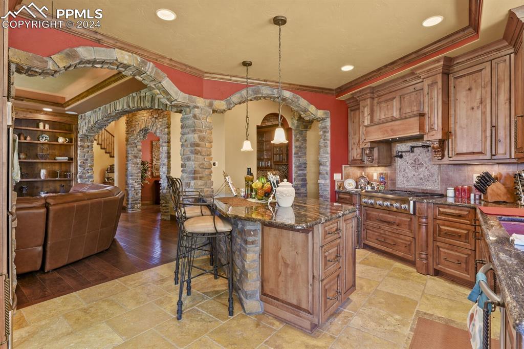 Image 10 of 50: Kitchen with light wood-type flooring, pendant lighting, stainless steel ga