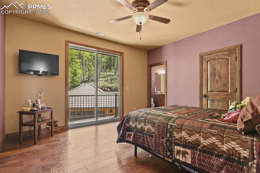 Image 25 of 50: Bedroom with ensuite bathroom, access to exterior, ceiling fan, and hardwoo