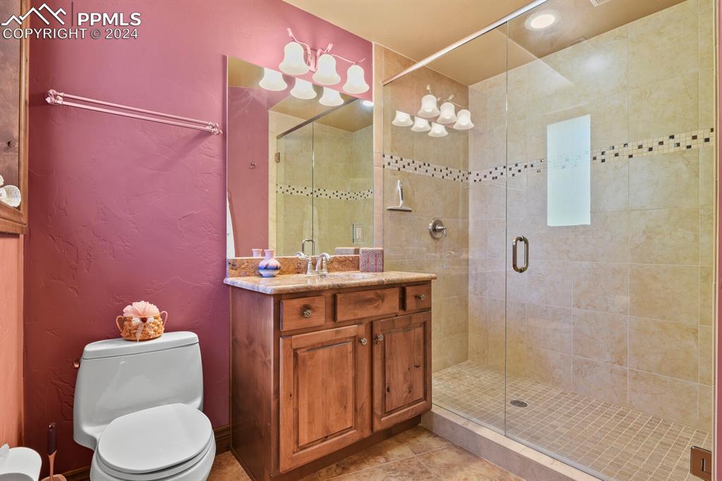 Image 26 of 50: Bathroom with tile floors, walk in shower, vanity, and toilet