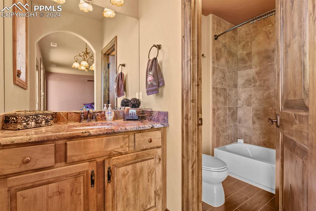 Image 28 of 50: Full bathroom featuring tile walls, a chandelier, tiled shower / bath combo