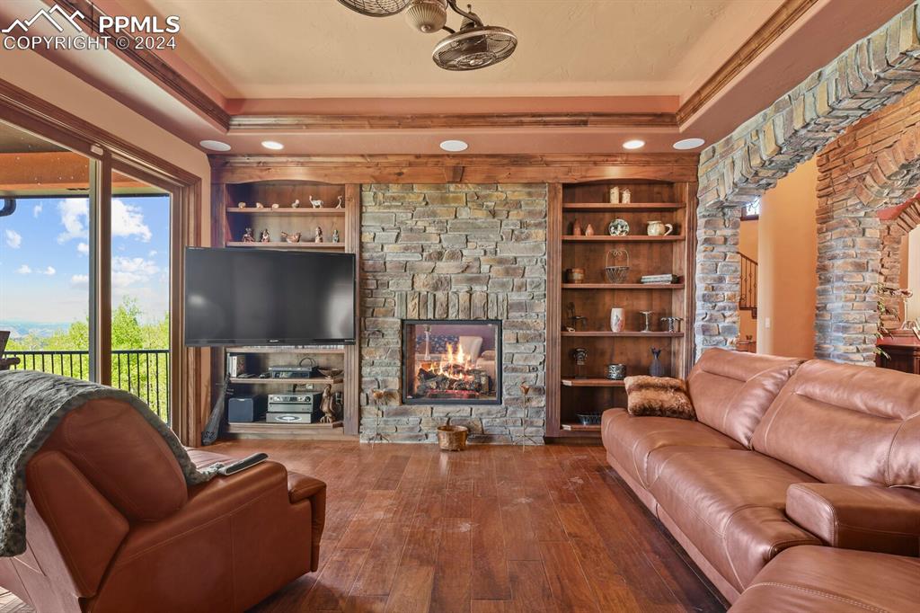 Image 3 of 50: Living room featuring a fireplace, a tray ceiling, hardwood / wood-style fl