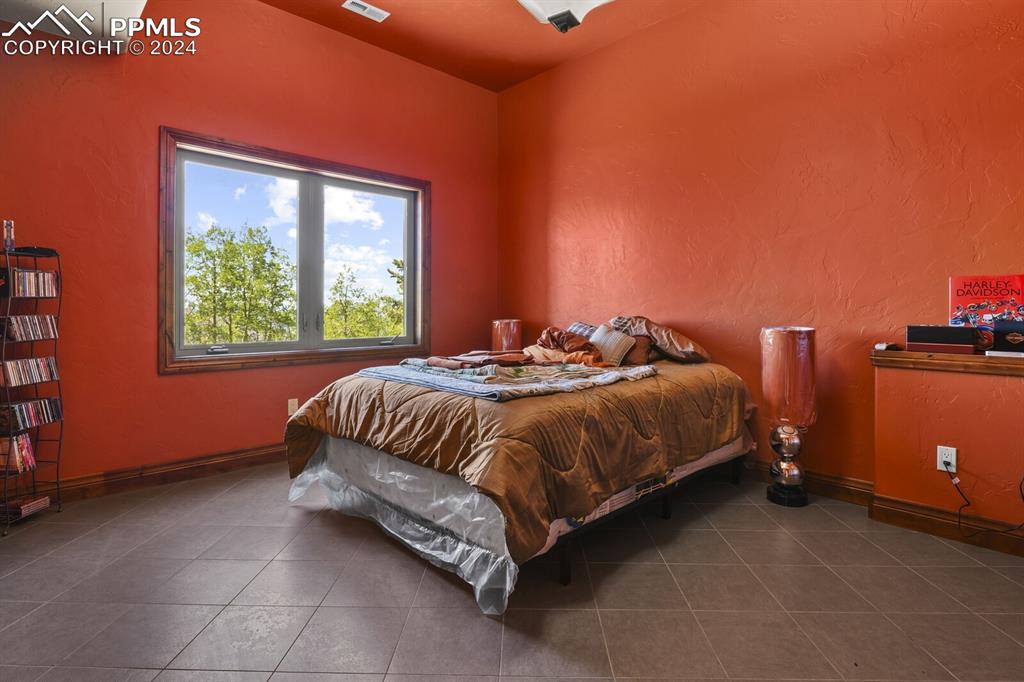 Image 35 of 50: Bedroom with dark tile flooring