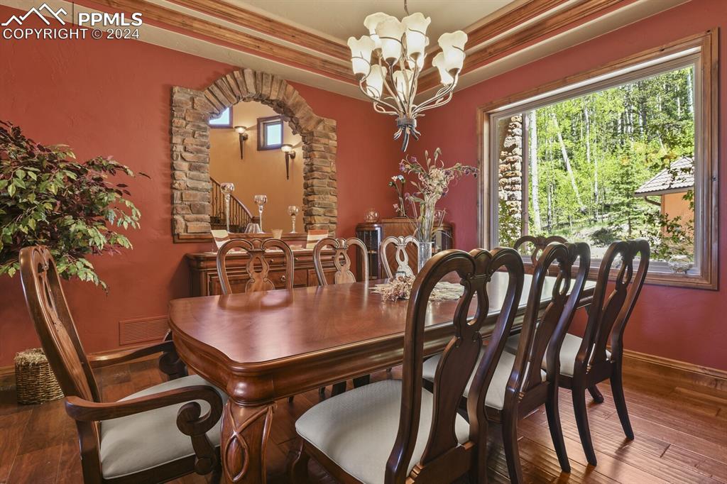Image 7 of 50: Dining space featuring a chandelier, a raised ceiling, and hardwood / wood-