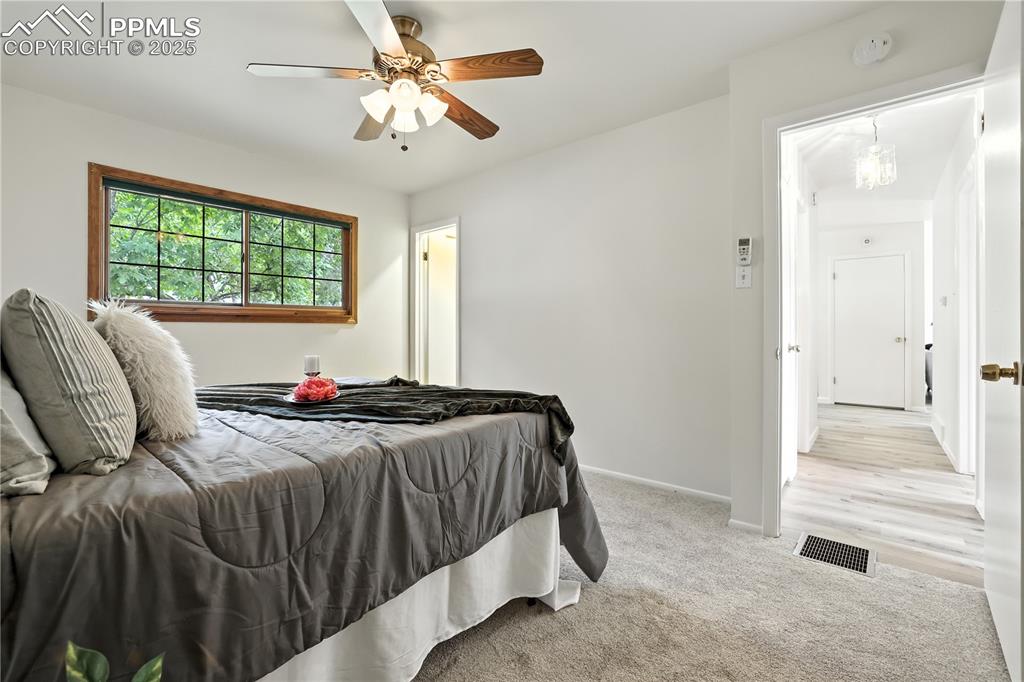Image 17 of 50: Primary bedroom with new carpet and a ceiling fan