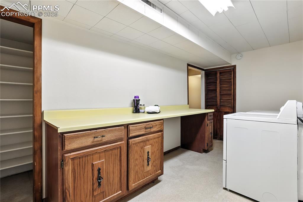 Image 37 of 50: Basement laundry with built-in cabinets and a storge room/pantry