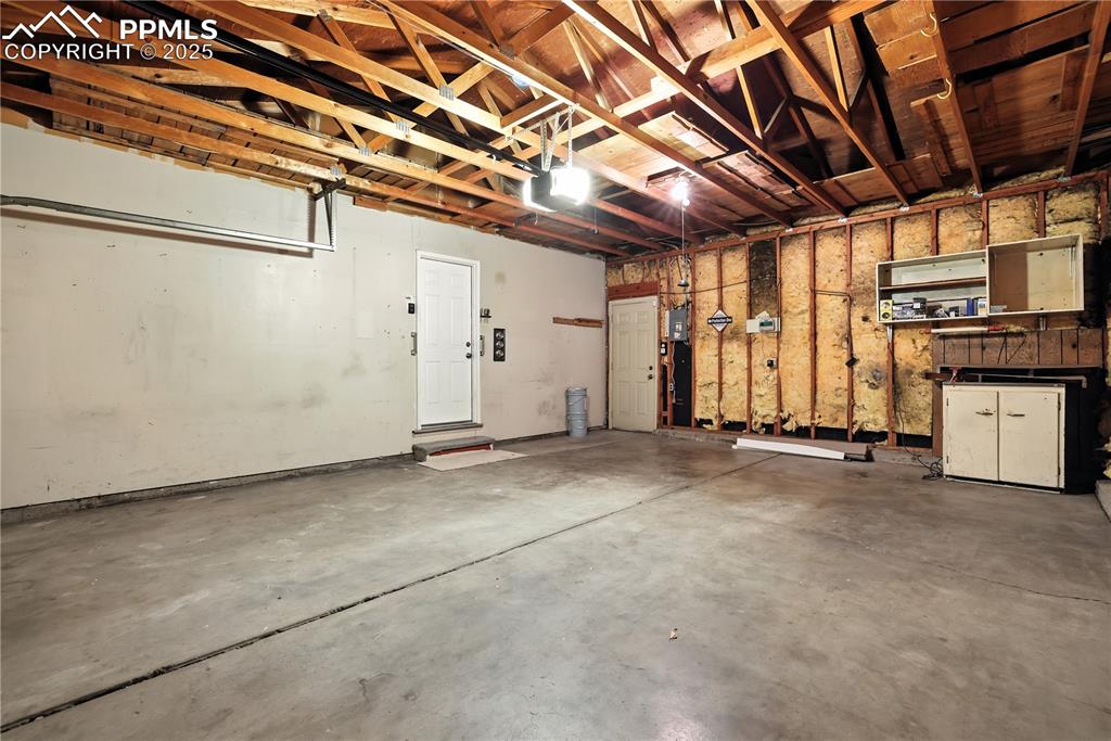 Image 48 of 50: Garage provides access to kitchen and back yard, with built-in workspace ar