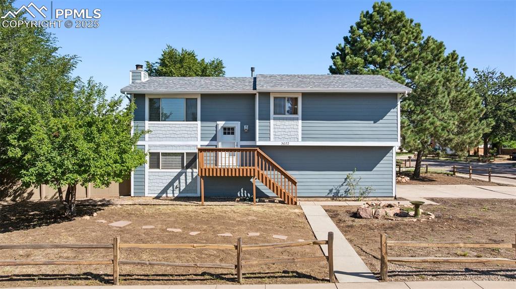 Caption: Raised ranch featuring stairs, a chimney, and roof with shingles
