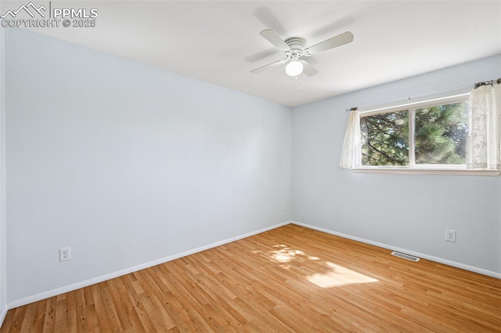 Image 11 of 35: Empty room with wood finished floors and a ceiling fan
