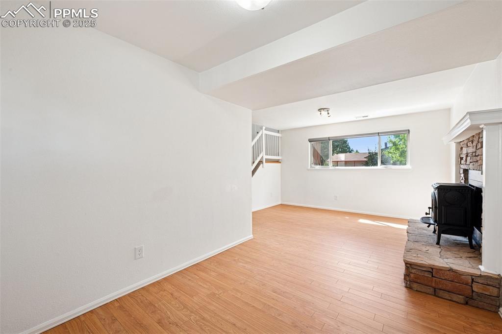 Image 20 of 35: Unfurnished living room with a wood stove, light wood-style floors, and sta