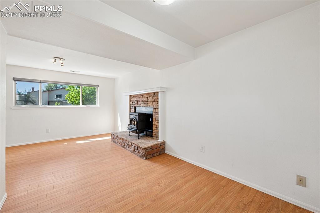 Image 21 of 35: Unfurnished living room with a wood stove and light wood finished floors