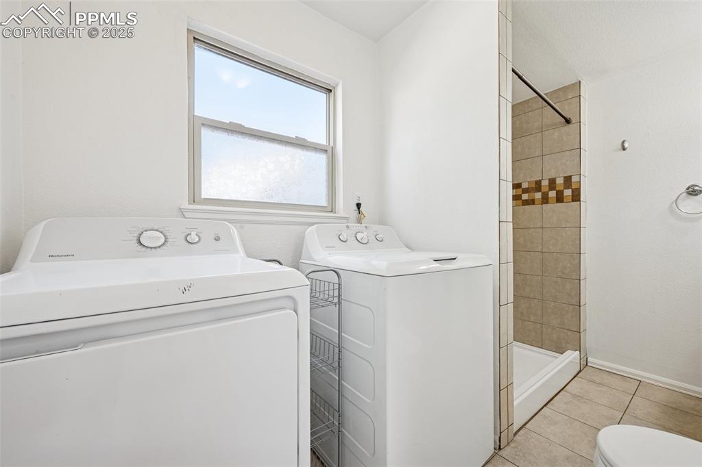 Image 22 of 35: Washroom with light tile patterned floors and separate washer and dryer