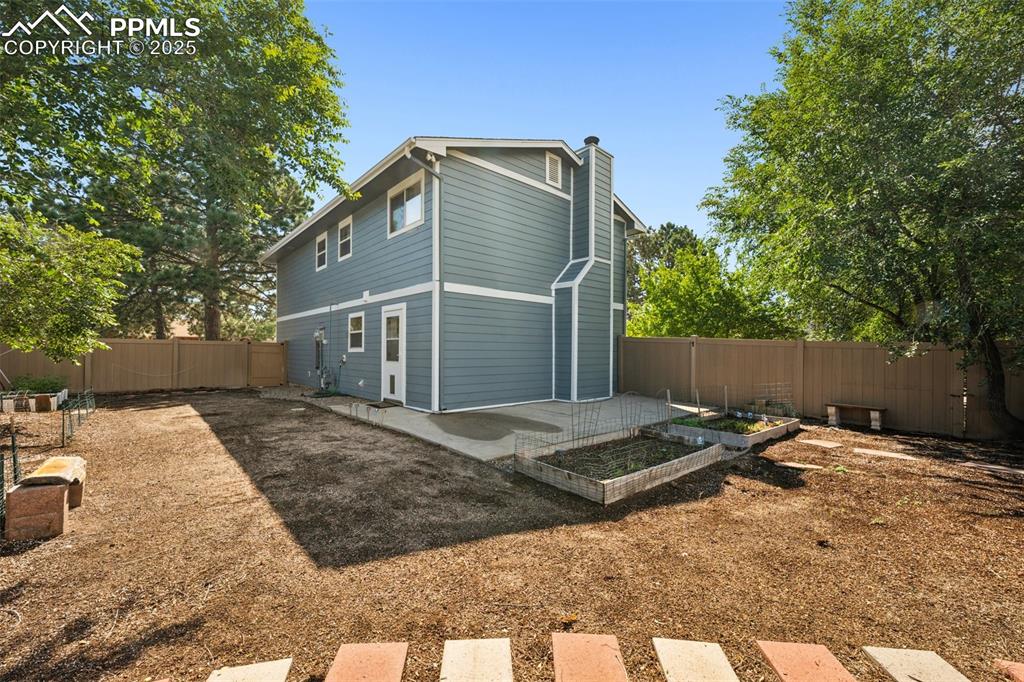 Image 26 of 35: Back of property with a vegetable garden, a fenced backyard, a chimney, and