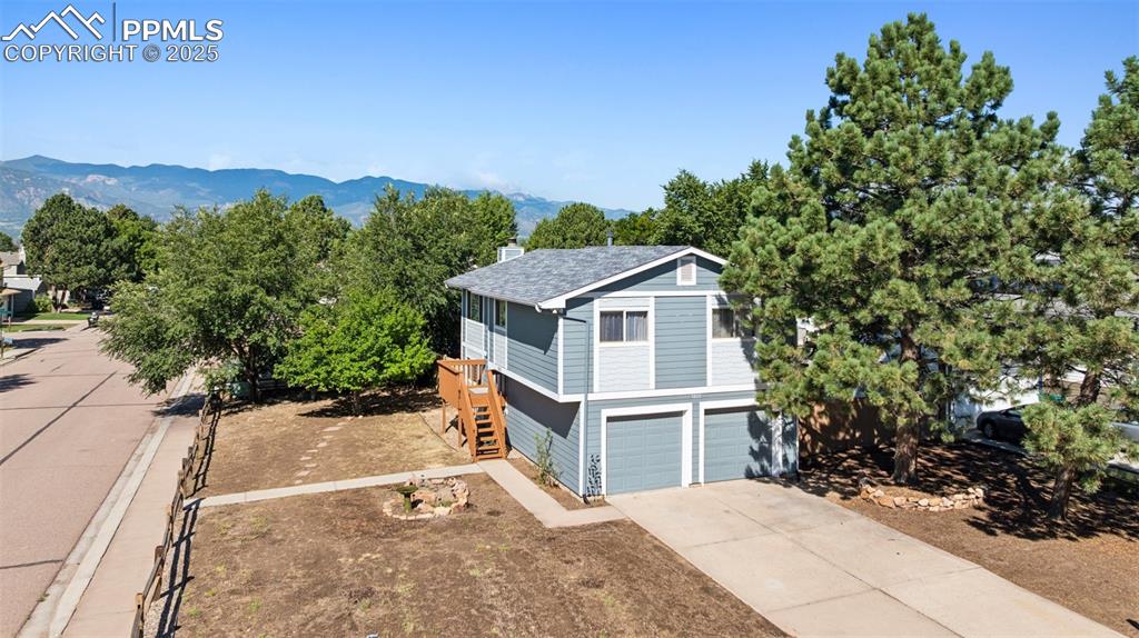 Image 29 of 35: View of front of house featuring stairs, concrete driveway, a chimney, a mo