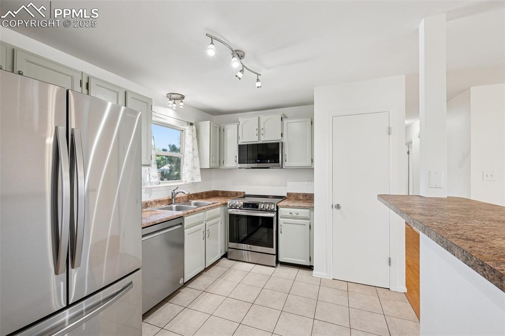 Image 3 of 35: Kitchen with stainless steel appliances, light tile patterned floors, white