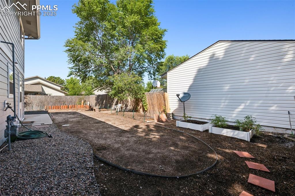 Image 33 of 35: Fenced backyard featuring a garden and a patio area