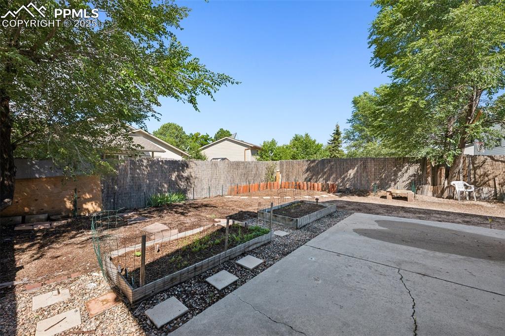 Image 35 of 35: Fenced backyard with a garden and a patio area