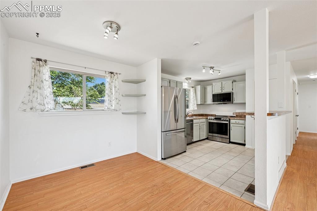 Image 5 of 35: Kitchen with open shelves, appliances with stainless steel finishes, light 