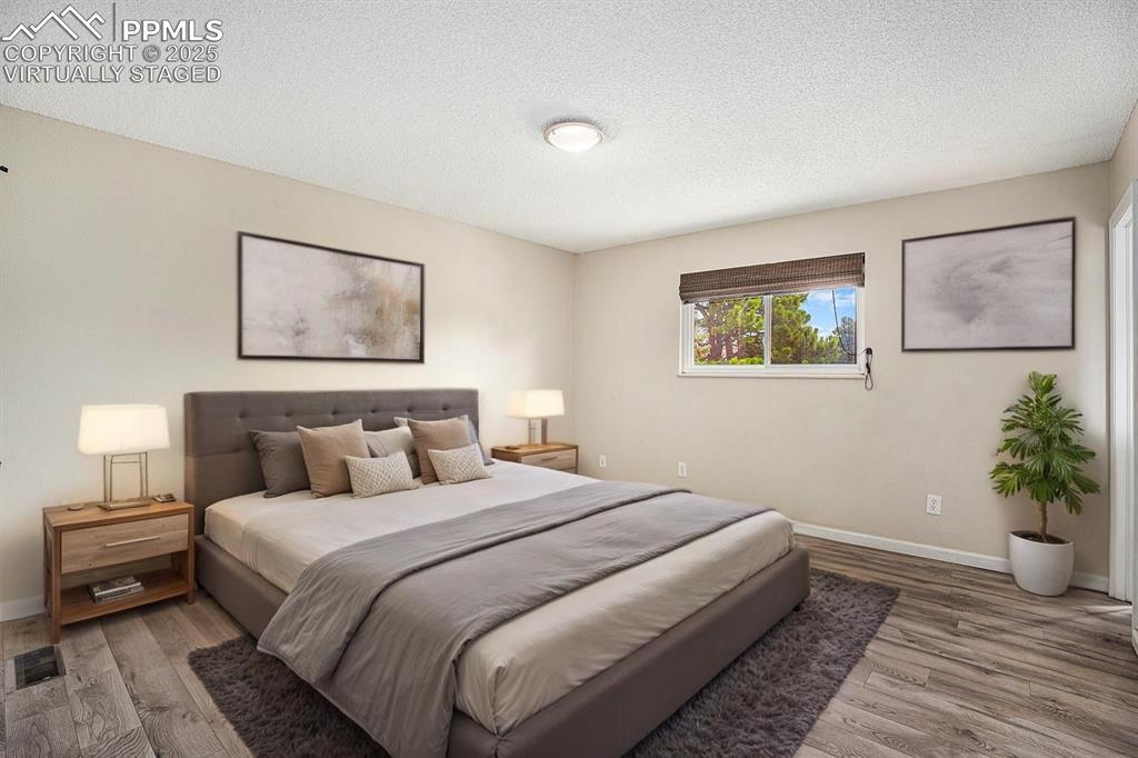 Image 10 of 31: Virtually Staged. Bedroom with a textured ceiling and light wood-style floo