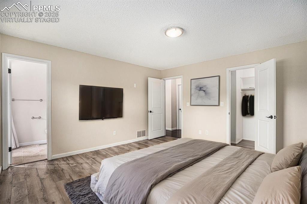 Image 12 of 31: Virtually Staged. Bedroom featuring a textured ceiling, wood finished floor