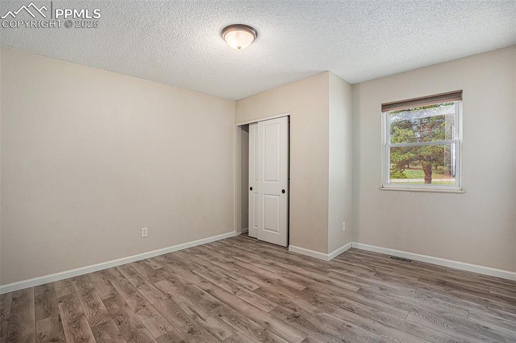 Image 18 of 31: Unfurnished bedroom featuring a textured ceiling, wood finished floors, and