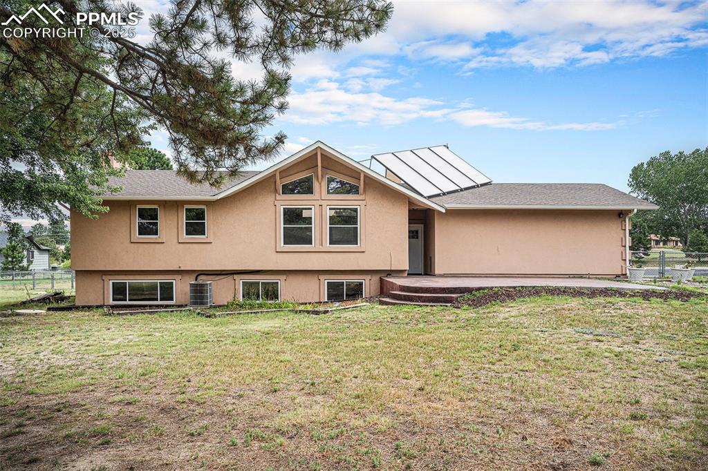 Image 2 of 31: Rear view of house featuring stucco siding and roof with shingles