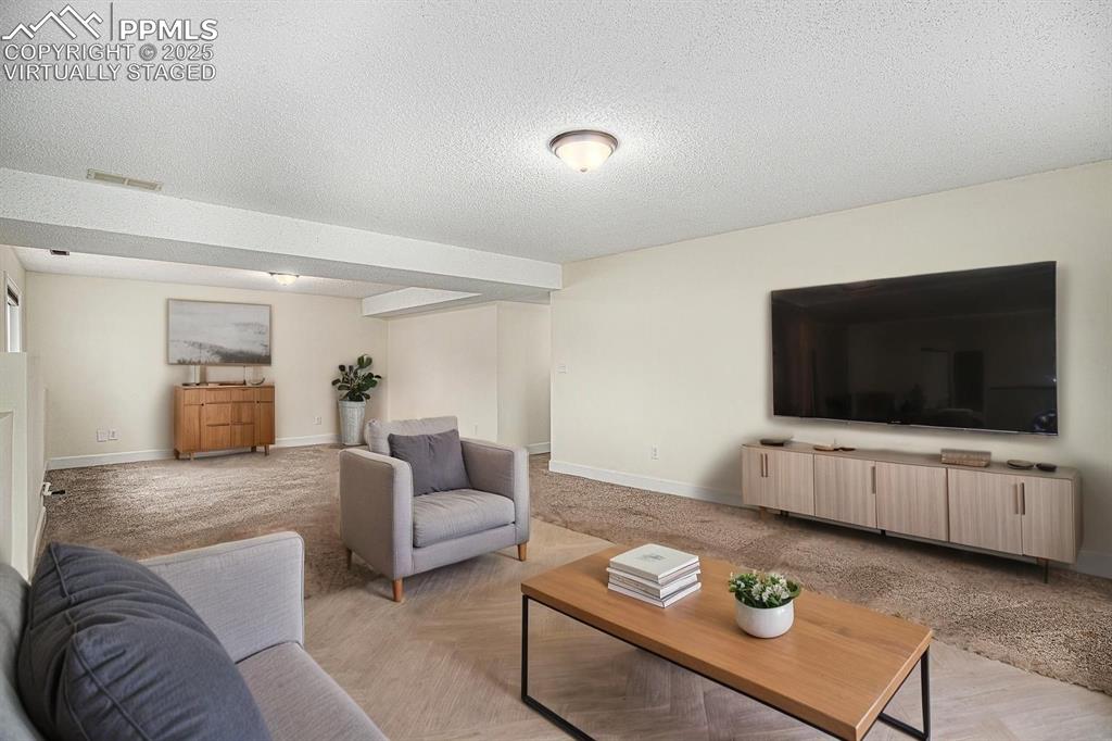 Image 21 of 31: Virtually Staged. Family room featuring light colored carpet and a textured