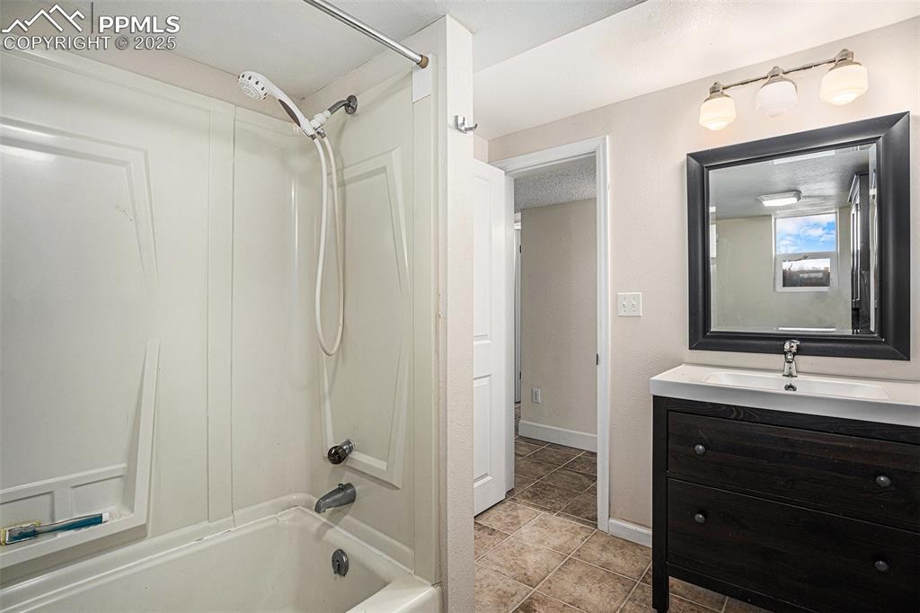 Image 24 of 31: Bathroom with bathtub / shower combination, vanity, and tile patterned floo