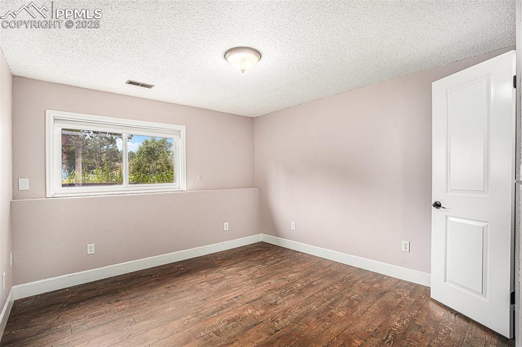 Image 25 of 31: Bedroom featuring wood-type flooring and a textured ceiling