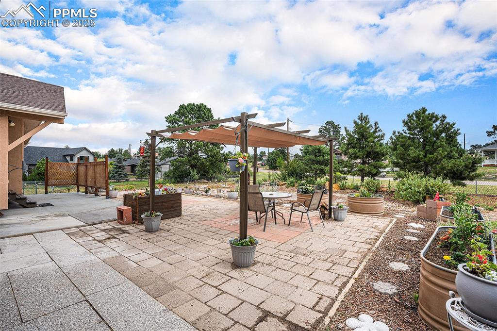 Image 29 of 31: View of patio featuring a pergola, a garden, and outdoor dining area