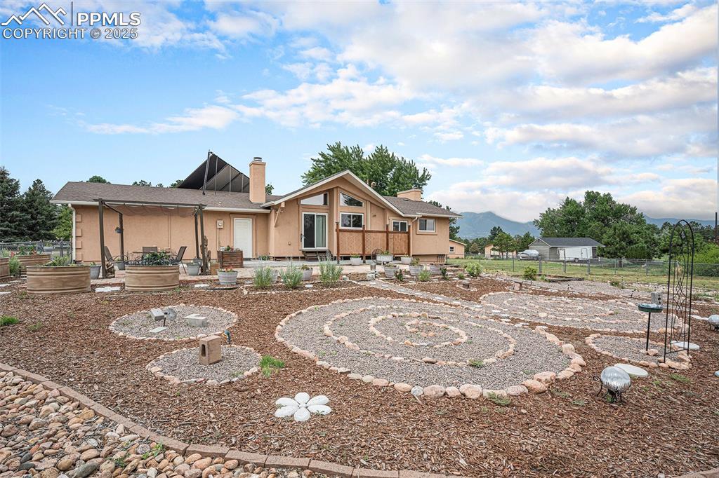 Image 30 of 31: View of front facade featuring a chimney, a vegetable garden, and a patio a
