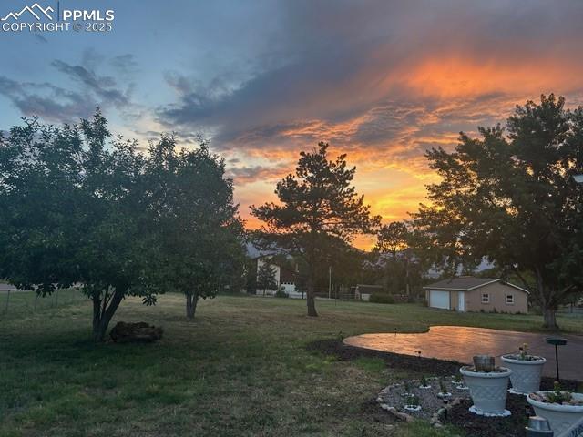 Image 31 of 31: Yard at dusk with a detached 3 car garage, a yard, and a garage