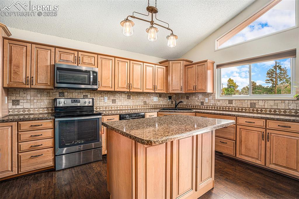 Image 7 of 31: Kitchen featuring lofted ceiling, appliances with stainless steel finishes,