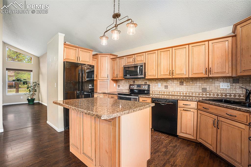 Image 8 of 31: Kitchen with lofted ceiling, appliances with stainless steel finishes, dark