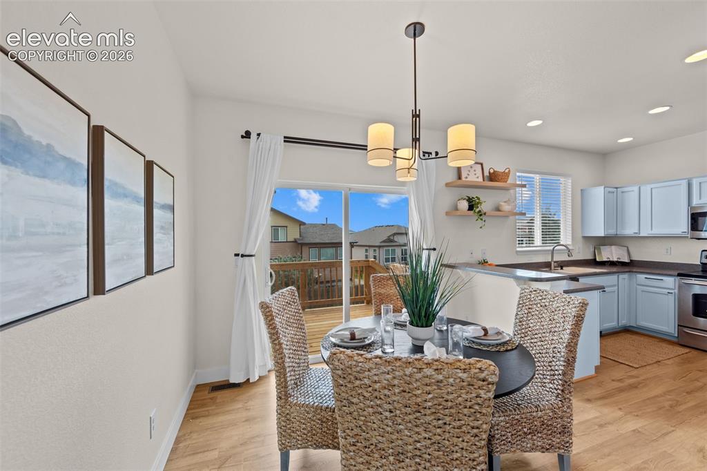 Image 11 of 33: Open-concept dining area featuring wood-finish flooring, a contemporary cha