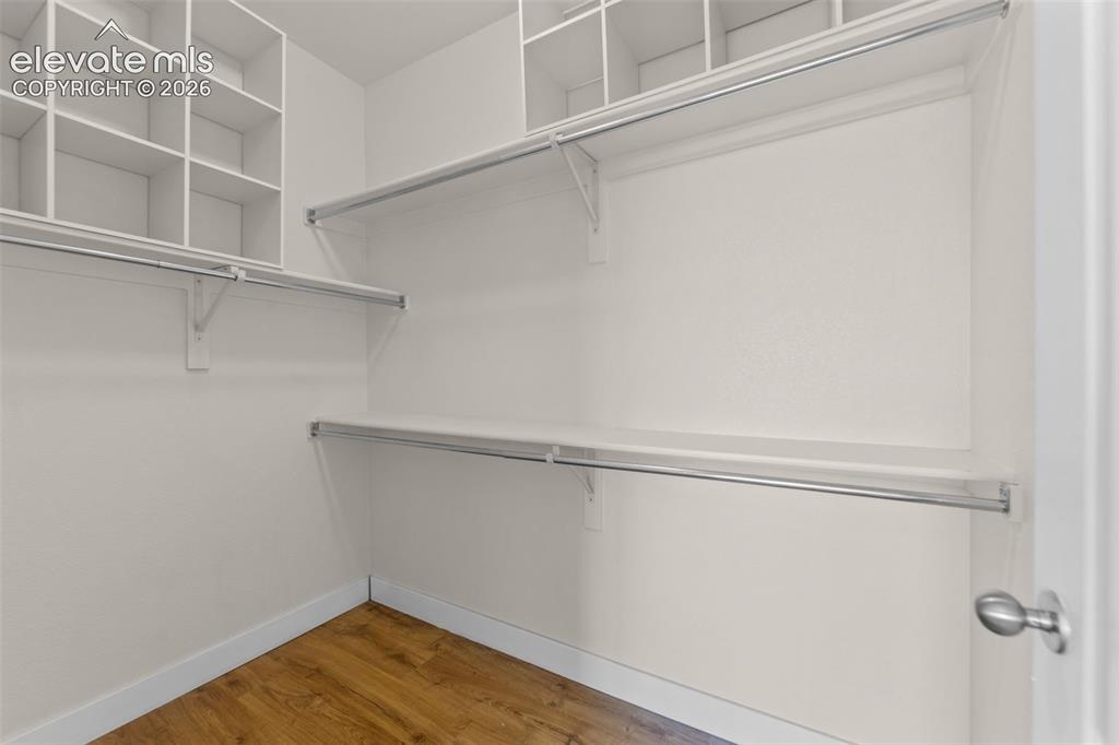 Image 16 of 33: Walk-in closet featuring wood-finish flooring, white walls, multiple storag