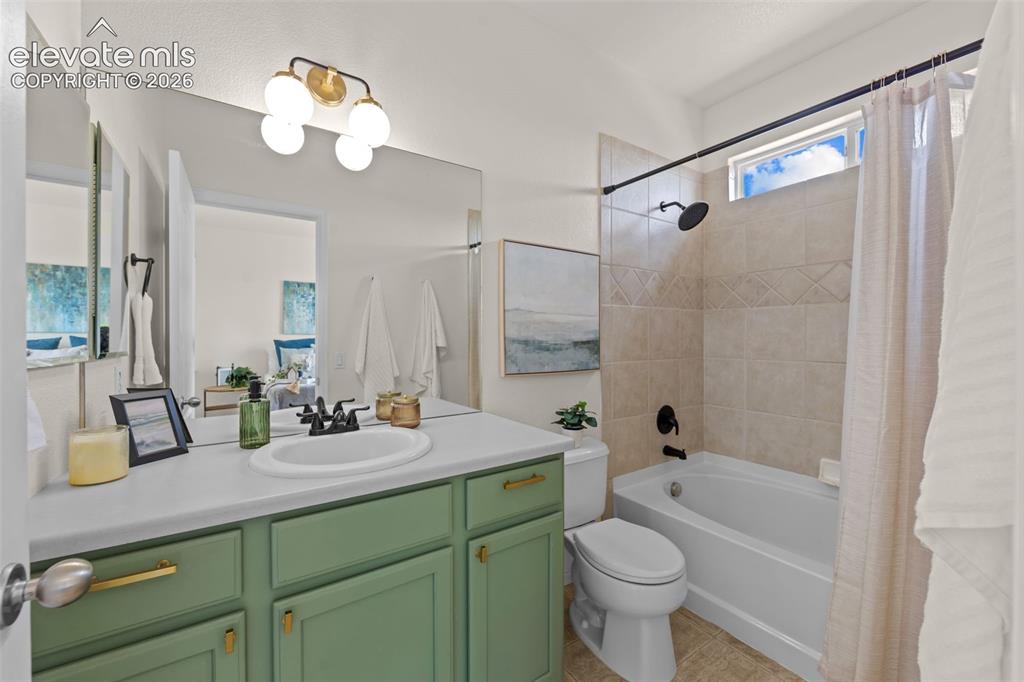 Image 17 of 33: Bathroom featuring a green vanity with gold-tone hardware, a white countert