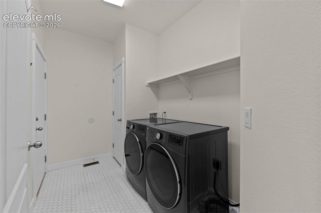 Image 18 of 33: Laundry room featuring hexagonal tile flooring, white walls, and a built-in