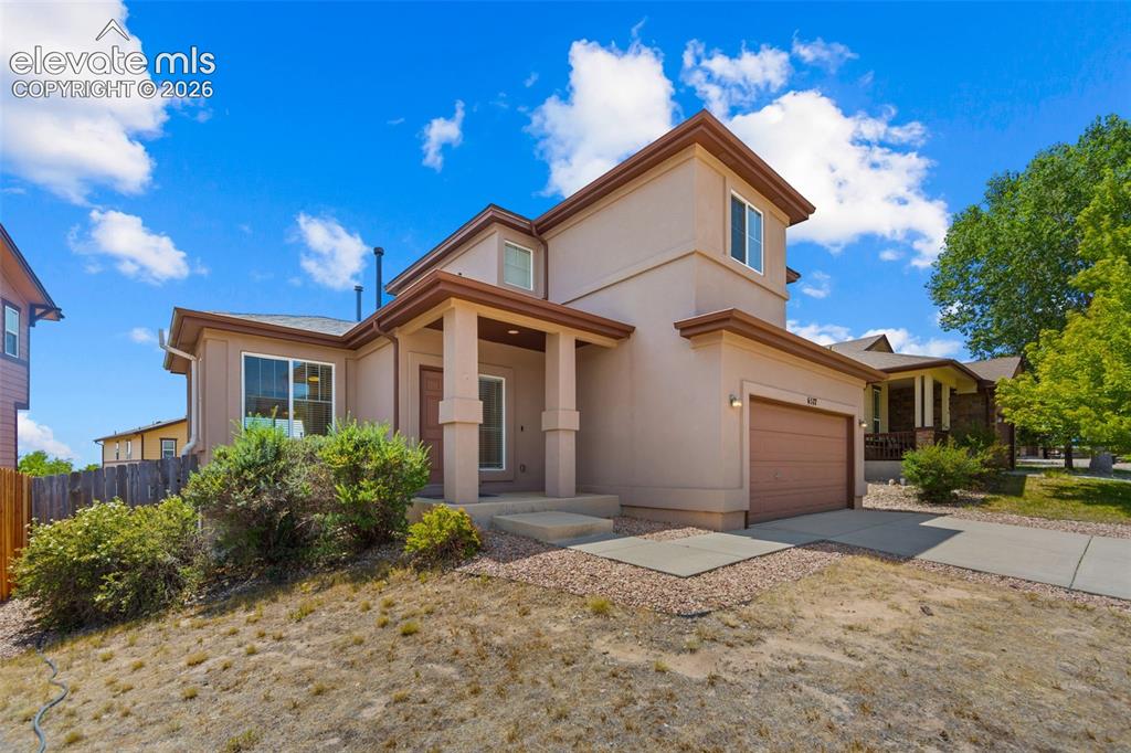 Image 2 of 33: Stucco exterior residence featuring a covered entry, attached garage with a