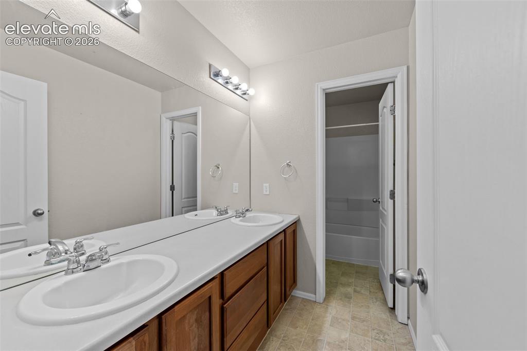 Image 23 of 33: Bathroom featuring a double vanity with integrated white sinks, wood-finish