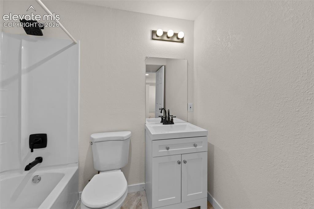 Image 27 of 33: White vanity with a single sink and matte black faucet, framed mirror, and 