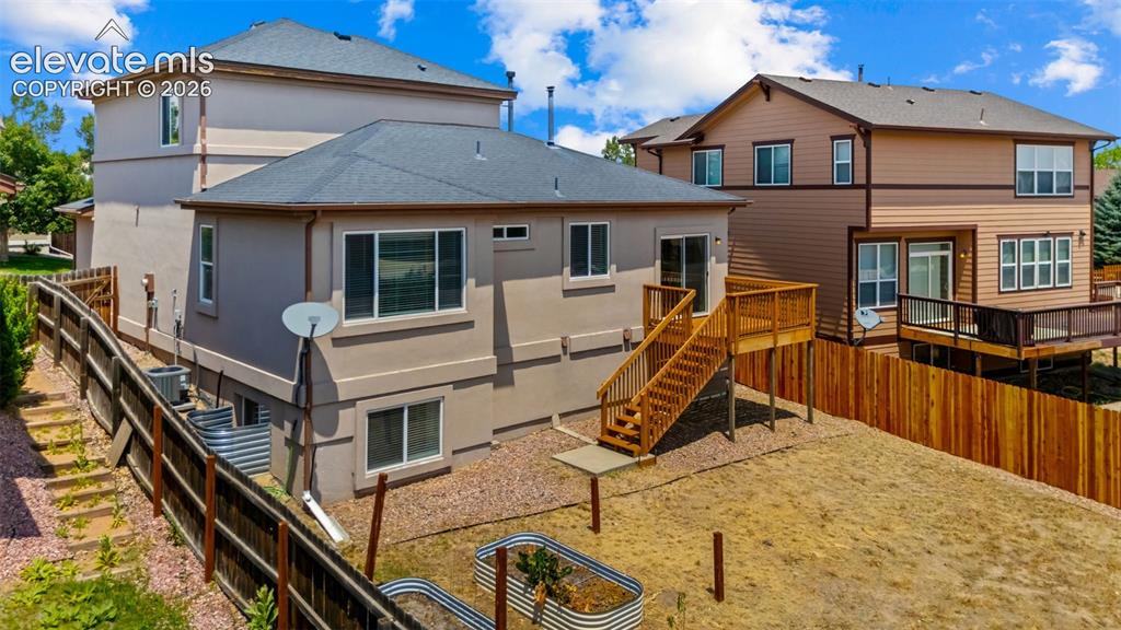Image 30 of 33: Rear exterior with a wood deck, sliding glass door access, and a wood priva
