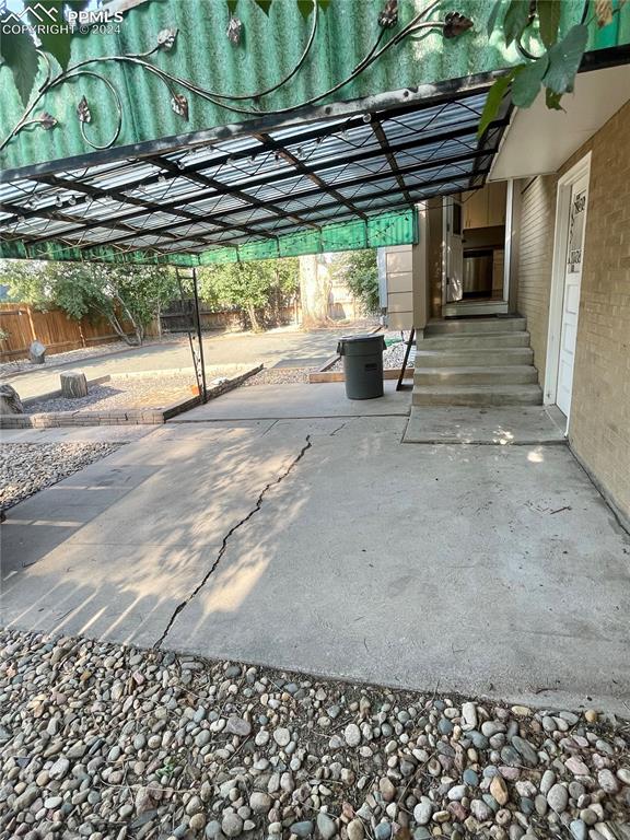 Image 42 of 47: View of patio and the steps from kitchen to patio and door to garage.