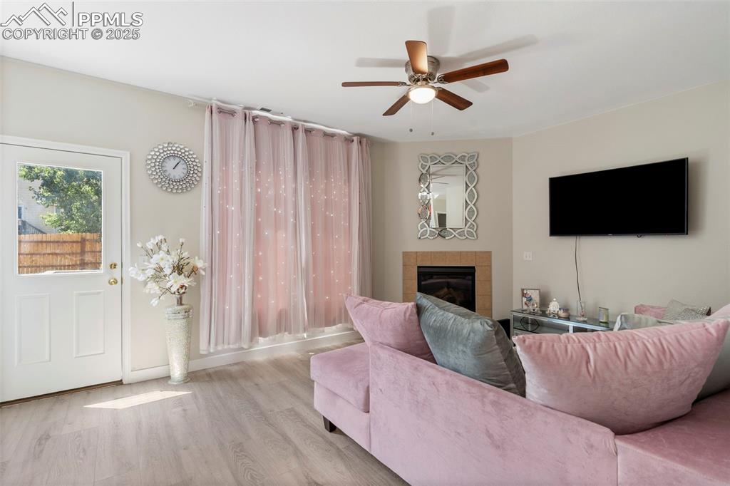 Image 10 of 25: Living room with wood finished floors, a fireplace, and ceiling fan