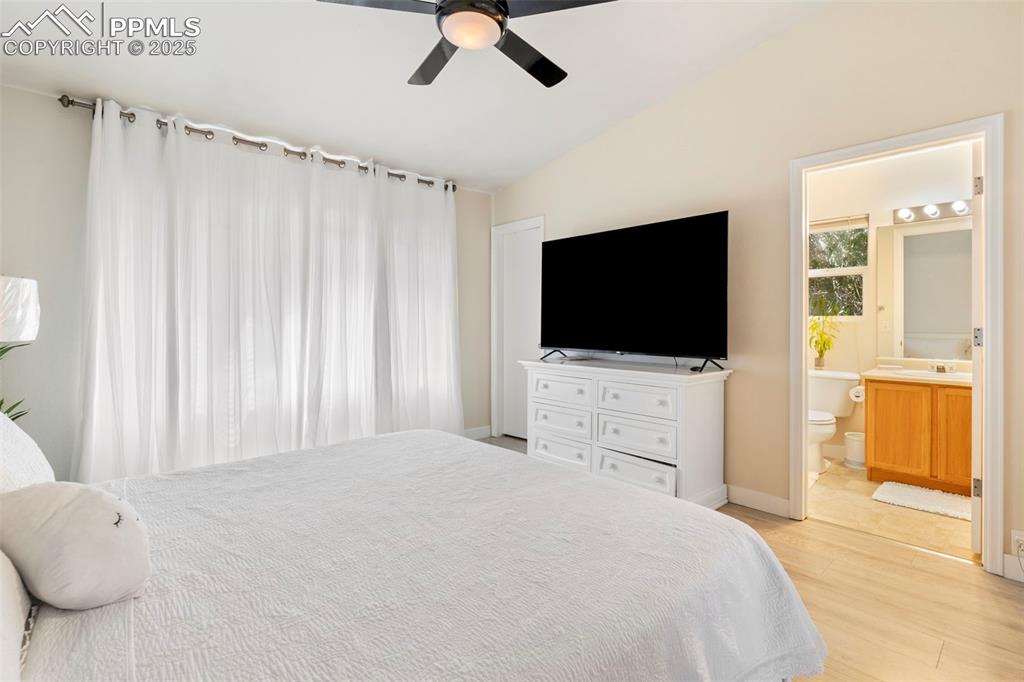 Image 14 of 25: Bedroom featuring vaulted ceiling, light wood finished floors, ceiling fan,